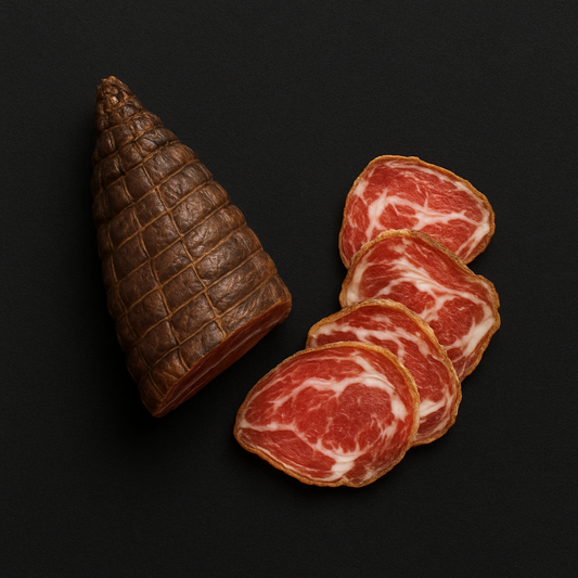 Homemade pancetta slices, cured and rolled with visible fat layers, arranged on wooden board with herbs