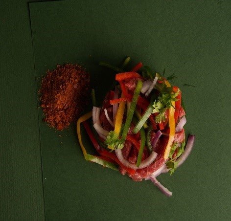 Raw veal fajita strips, thinly sliced and marinated with bell peppers and spices, arranged on butcher tray